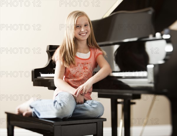 Portrait of girl (8-9) sitting by piano. Photo: Mike Kemp