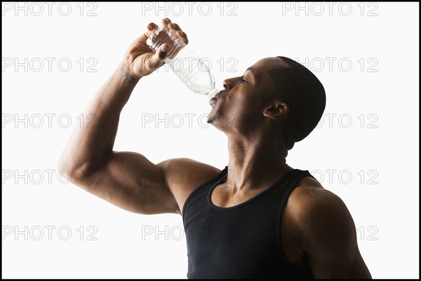 Studio shot of man drinking water from bottle. Photo : Mike Kemp