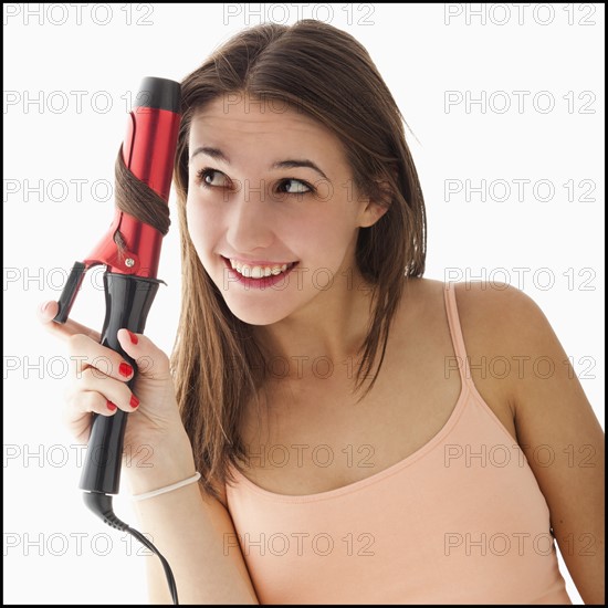 Young woman curling hair. Photo : Mike Kemp