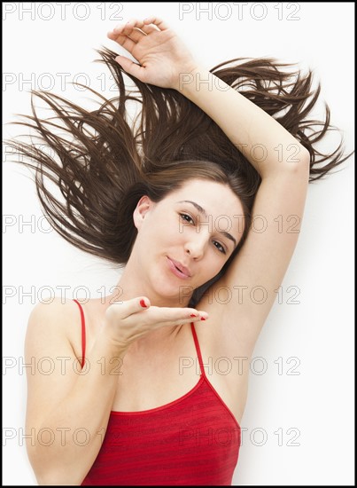 Studio portrait of young woman blowing a kiss. Photo : Mike Kemp