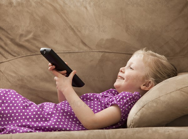 Girl (2-3) watching TV on sofa. Photo : Mike Kemp