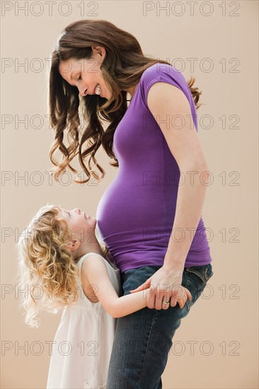 Portrait of girl (2-3) and pregnant mother holding hands. Photo : Mike Kemp