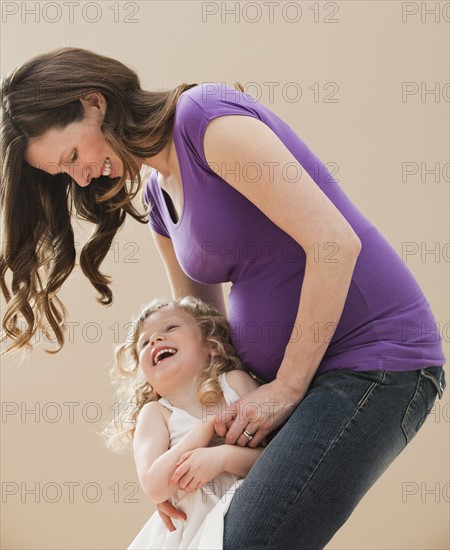 Portrait of girl (2-3) and pregnant mother embracing. Photo : Mike Kemp