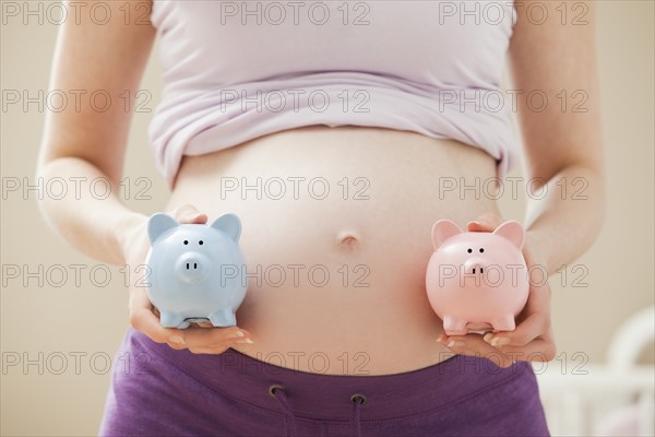 Young pregnant woman holding blue and pink piggybanks. Photo: Mike Kemp