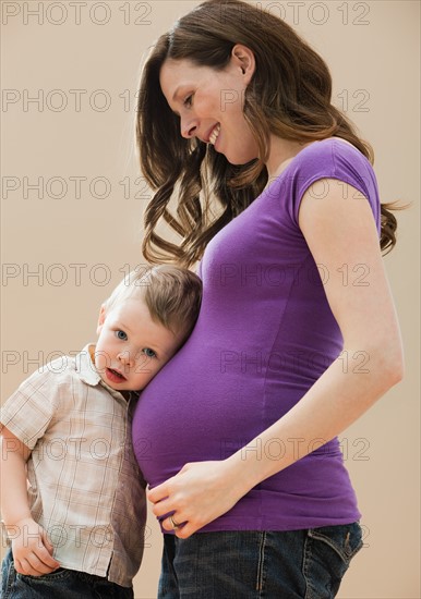 Portrait of boy (2-3) leaning pregnant mother's belly. Photo: Mike Kemp