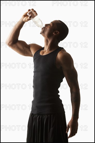 Studio shot of man drinking water from bottle. Photo : Mike Kemp