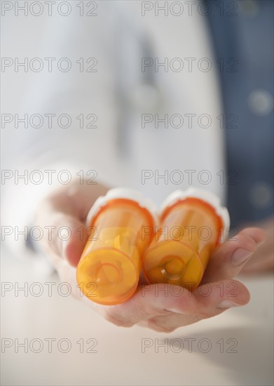 Hand holding pill bottles. Photo : Jamie Grill Photography