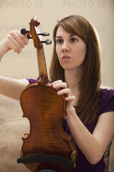 Young woman tuning violin. Photo : Mike Kemp