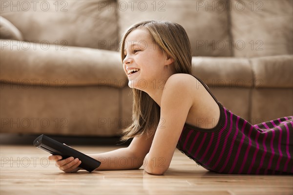 Girl (10-11) lying on floor, watching TV. Photo: Mike Kemp