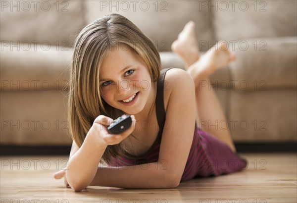 Girl (10-11) lying on floor, watching TV. Photo: Mike Kemp