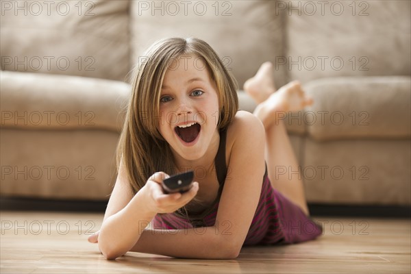 Girl (10-11) lying on floor, watching TV. Photo : Mike Kemp