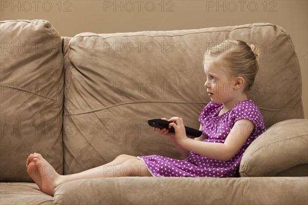 Girl (2-3) watching TV on sofa. Photo : Mike Kemp