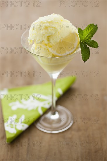 Close up of ice cream with mint leaf and lemon slice.