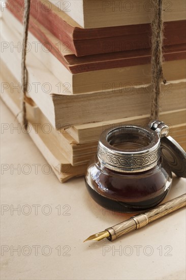 Close up antique ink well, pen and books.