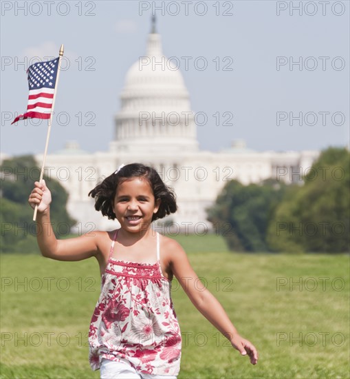 USA, Washington DC, girl (10-11) with US flag running in front of Capitol Building. Photo : Chris Grill