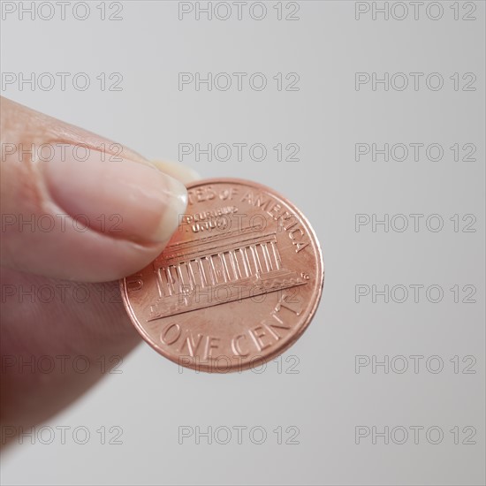 Studio shot of woman holding one cent coin.