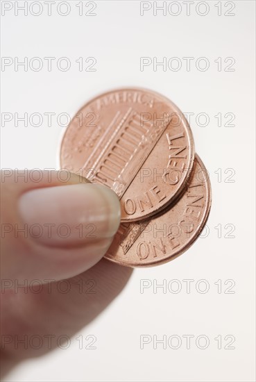 Studio shot of woman holding two one cent coins.