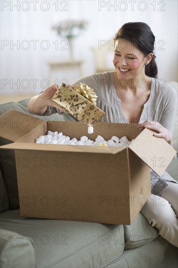 Young woman opening box with gift.