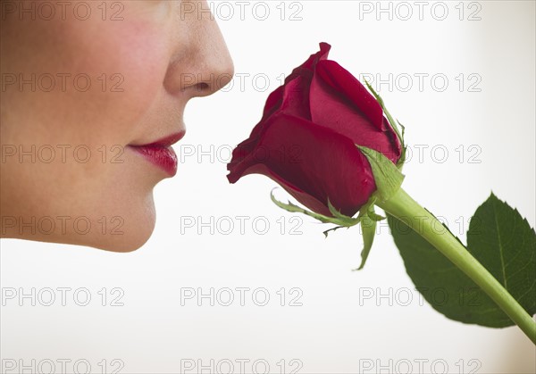 Studio shot of woman smelling red rose.