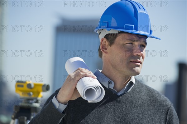 Construction worker holding rolled up blueprint.