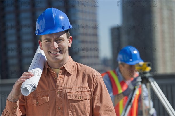 USA, New Jersey, Jersey City, portrait of construction worker holding rolled up blueprint.