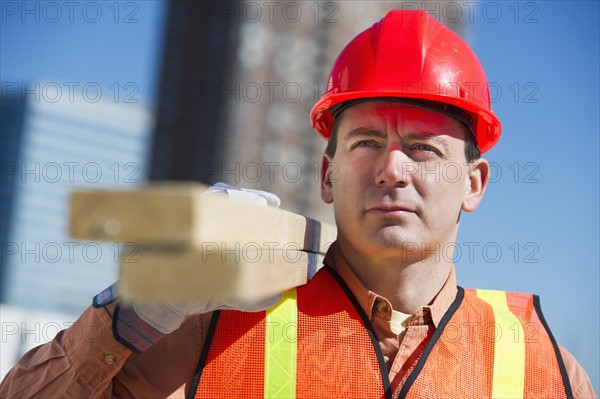 USA, New Jersey, Jersey City, construction worker carrying planks.