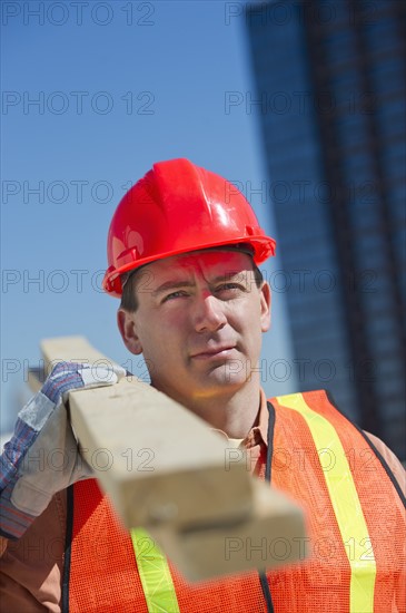 Construction worker carrying planks.