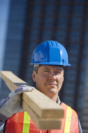 Construction worker carrying planks.