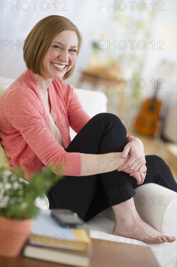 Woman sitting on sofa smiling.