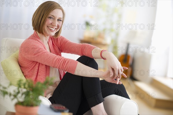 Woman sitting on sofa smiling.