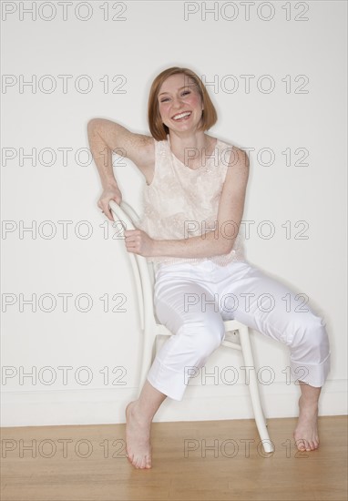 Studio shot of woman sitting on chair and smiling.