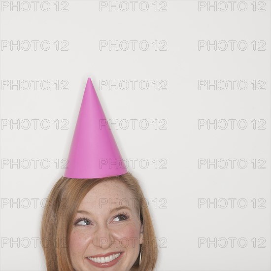 Studio shot of woman wearing pink party hat.