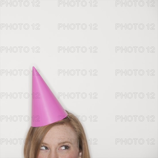 Studio shot of woman wearing pink party hat.