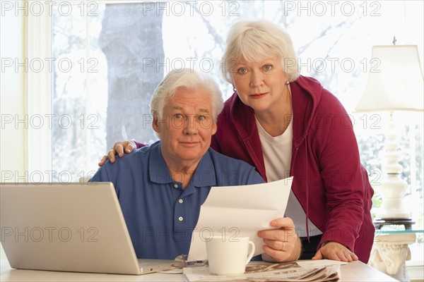 USA, Virginia, Richmond, portrait of senior couple paying bills with laptop. Photo : Mark Edward Atkinson