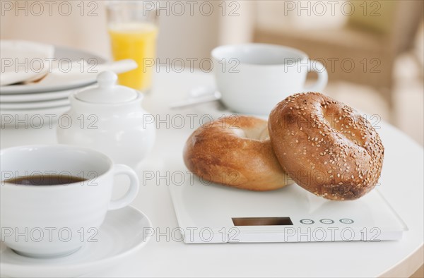 Bagels on weight scale on kitchen table.