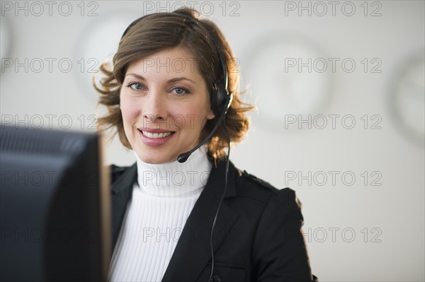 Portrait of smiling woman with headset in customer service office.