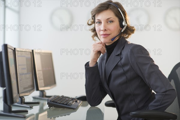 Portrait of smiling woman with headset in customer service office.