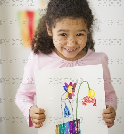 Smiling girl (6-7) showing her drawing.
