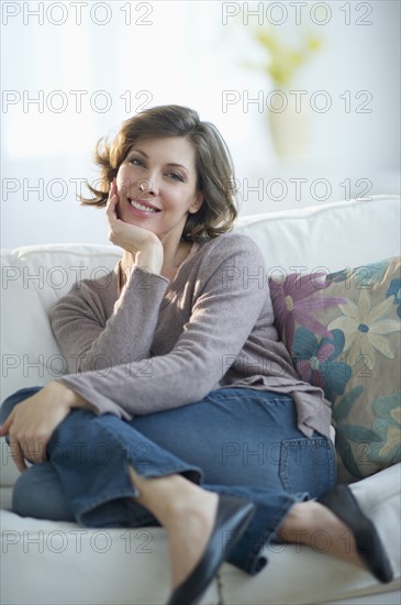 Portrait of smiling woman sitting on sofa.