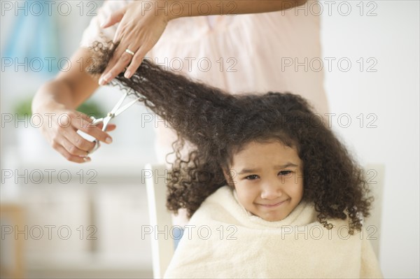 Mother cutting daughter's (6-7) hair.