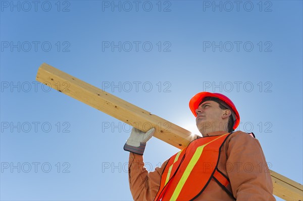 Construction worker carrying planks.