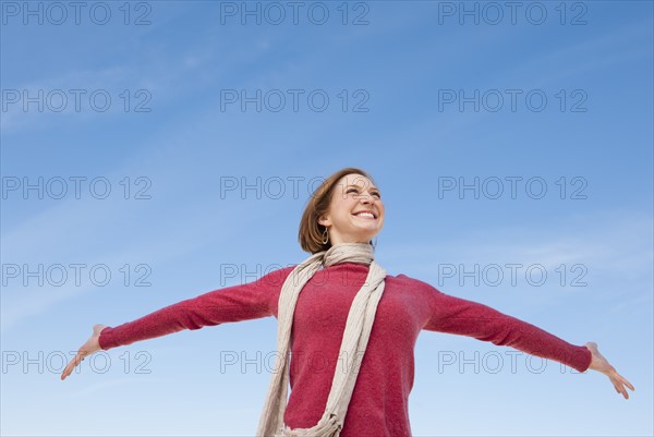 Woman raising hands against sky.