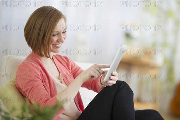 Woman sitting on sofa and using digital tablet.