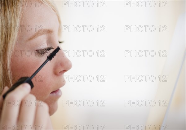 Young woman applying mascara. Photo : Jamie Grill Photography