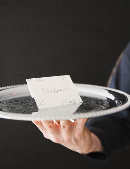 Hand holding tray with envelope. Photo : Jamie Grill Photography