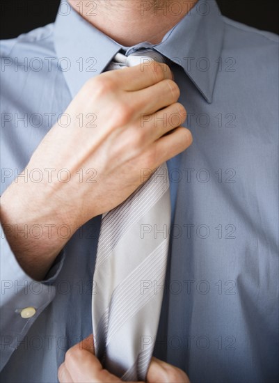 Businessman adjusting tie. Photo: Jamie Grill Photography