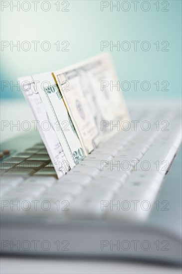 Studio shot of banknotes in computer keyboard. Photo : Jamie Grill Photography
