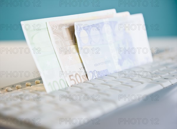 Studio shot of banknotes in computer keyboard. Photo : Jamie Grill Photography