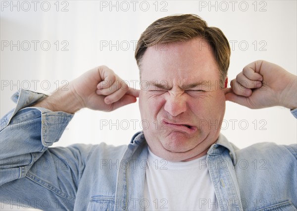 Man blocking ears with fingers. Photo : Jamie Grill Photography