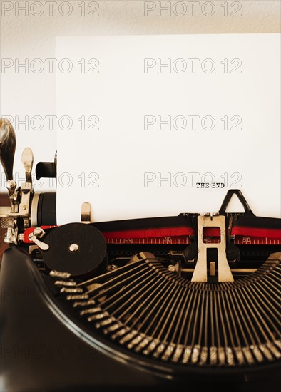 Close up of antique typewriter with "the end" print on page.